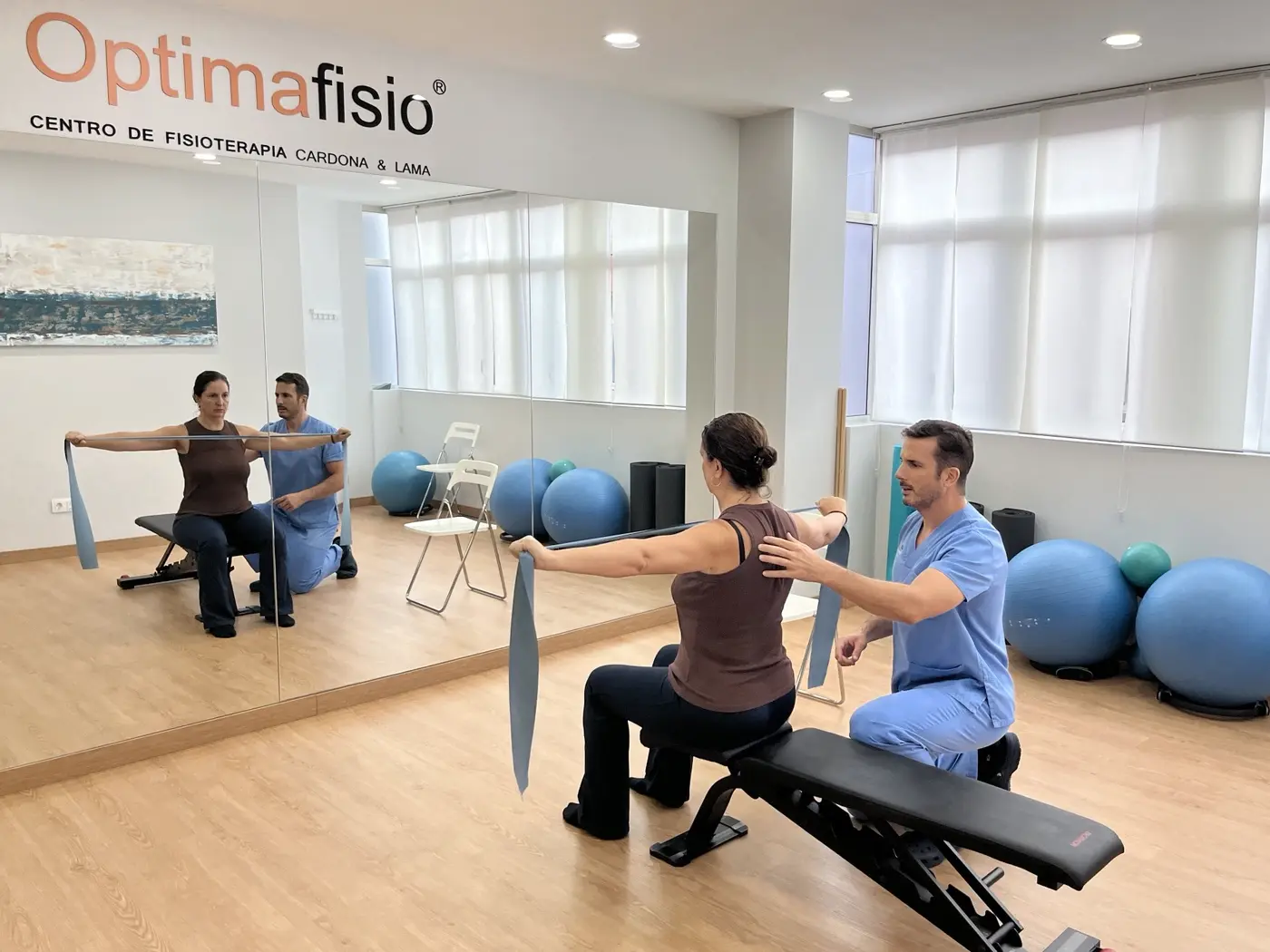 Isaac Cardona supervisando un ejercicio con banda elástica en Optimafisio
